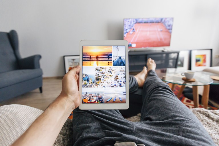 Man relaxing on the sofa in apartment and using digital tablet, personal perspective