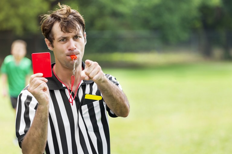 Soccer referee points and holds up red card